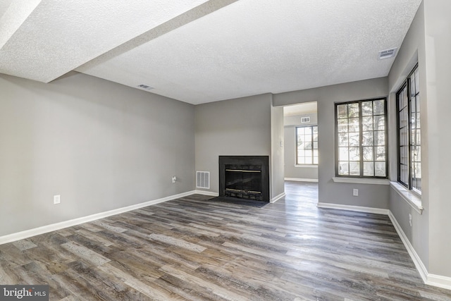 unfurnished living room featuring hardwood / wood-style flooring and a textured ceiling