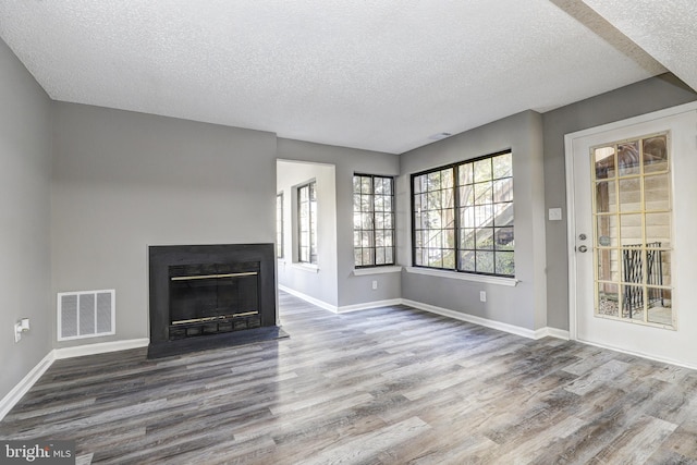 unfurnished living room featuring hardwood / wood-style floors and a textured ceiling