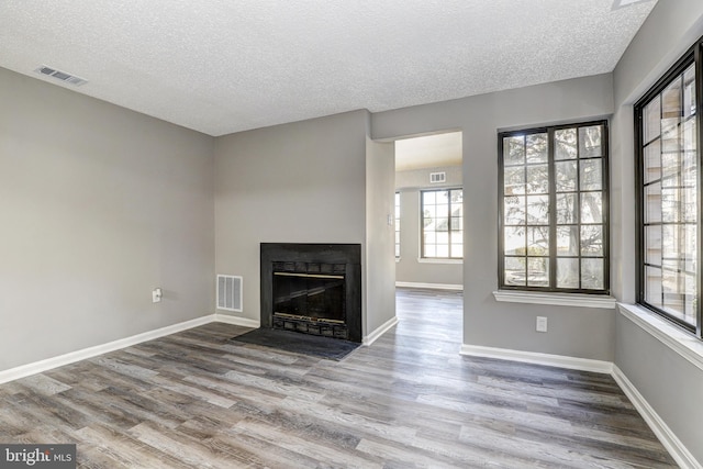 unfurnished living room with wood-type flooring and a textured ceiling