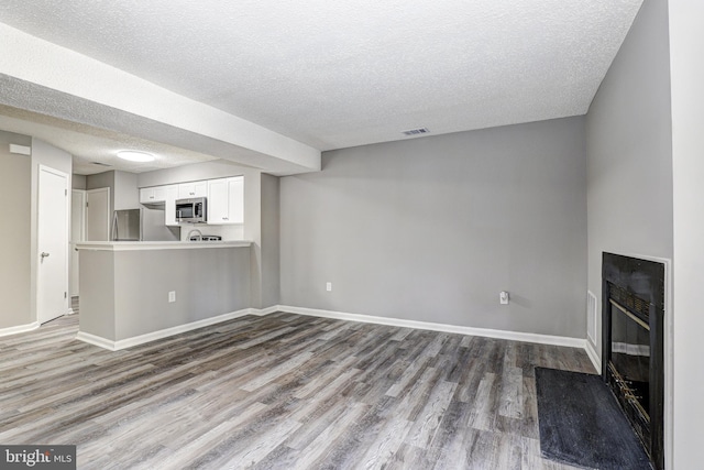 unfurnished living room with hardwood / wood-style floors and a textured ceiling