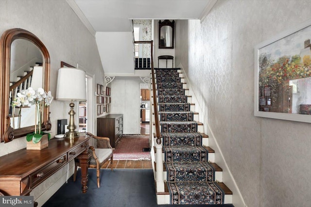 staircase with wood-type flooring and ornamental molding