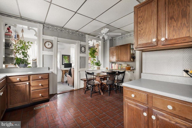 kitchen with decorative backsplash, a drop ceiling, and ceiling fan