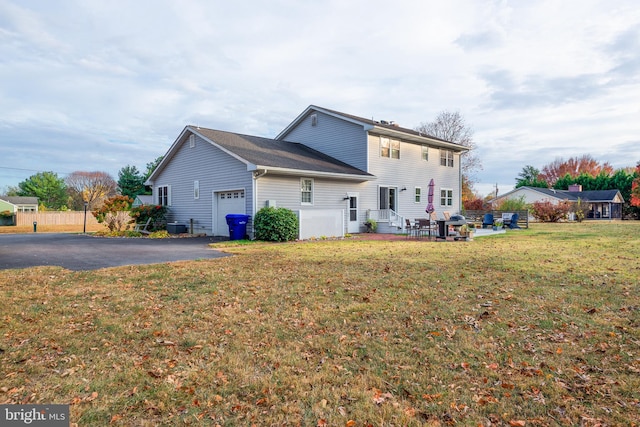 back of property with a garage and a lawn