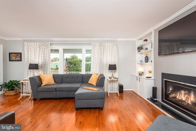 living room featuring built in features, ornamental molding, and light hardwood / wood-style flooring