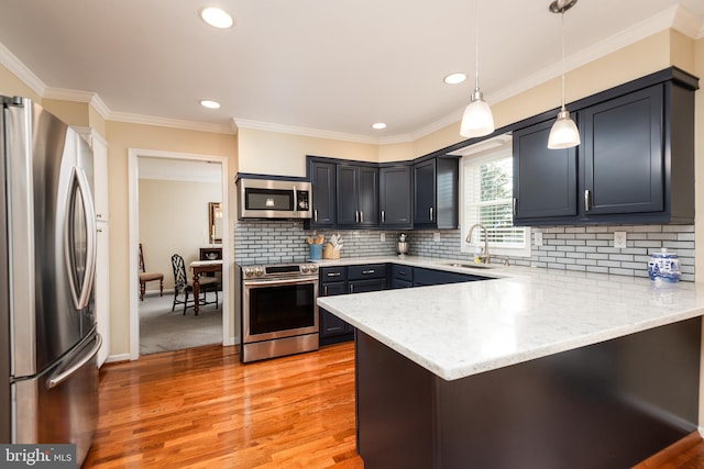 kitchen featuring sink, kitchen peninsula, appliances with stainless steel finishes, crown molding, and pendant lighting