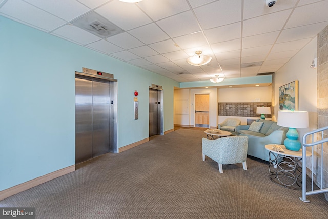 carpeted living room with elevator and a paneled ceiling