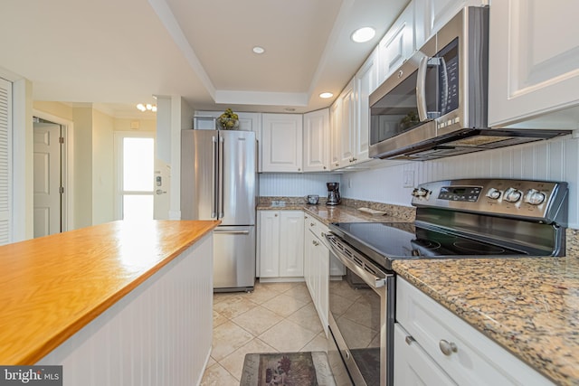 kitchen with stainless steel appliances, white cabinets, light tile patterned floors, and light stone counters