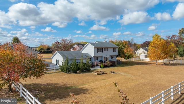 back of property featuring a rural view and a yard