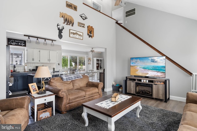 living room with ceiling fan, light hardwood / wood-style flooring, and high vaulted ceiling