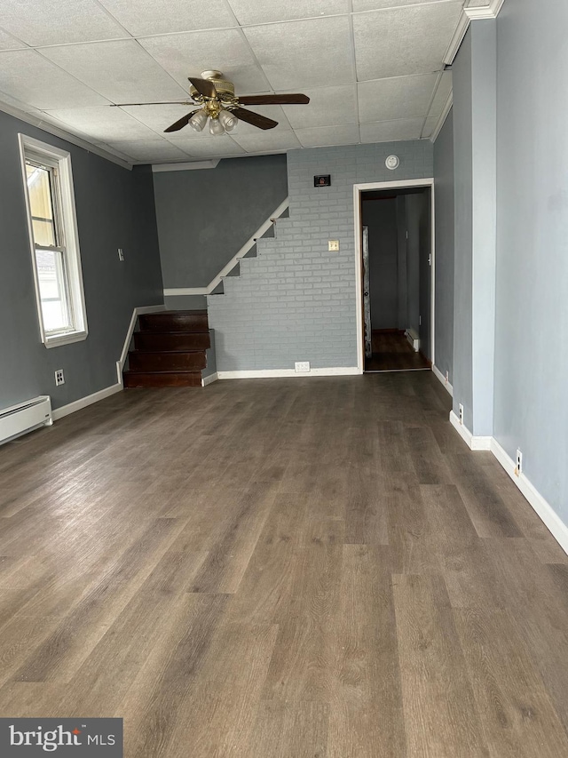 empty room with ceiling fan, dark hardwood / wood-style floors, and brick wall