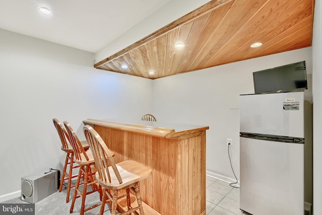 bar featuring stainless steel fridge, wooden ceiling, and light tile patterned flooring