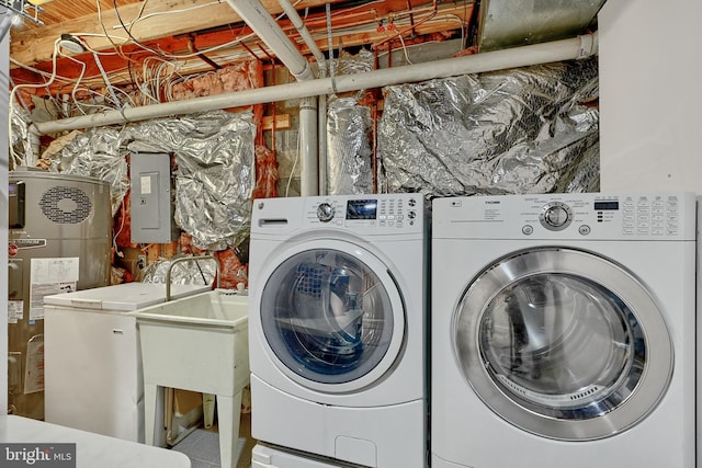 laundry area with heat pump water heater, electric panel, and washing machine and clothes dryer