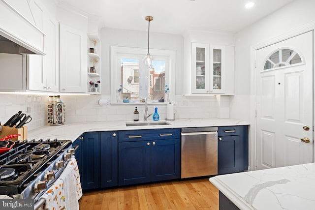 kitchen featuring stainless steel appliances, blue cabinets, white cabinets, sink, and light wood-type flooring