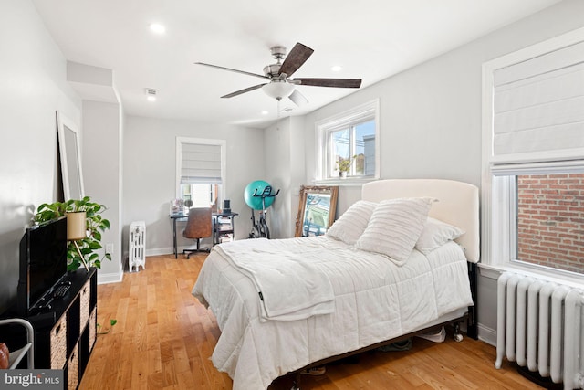 bedroom featuring light hardwood / wood-style floors, ceiling fan, and radiator heating unit