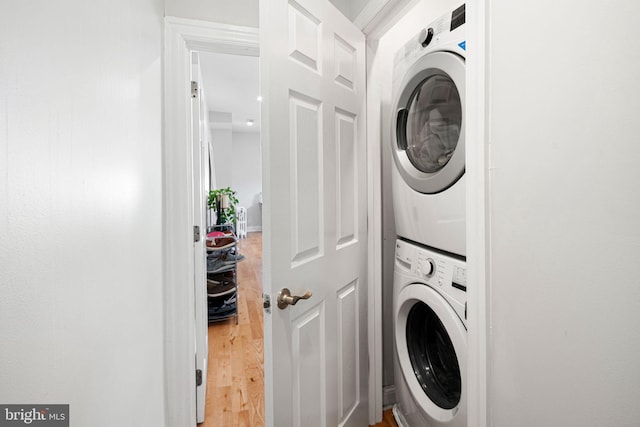 clothes washing area featuring stacked washer / dryer and hardwood / wood-style flooring