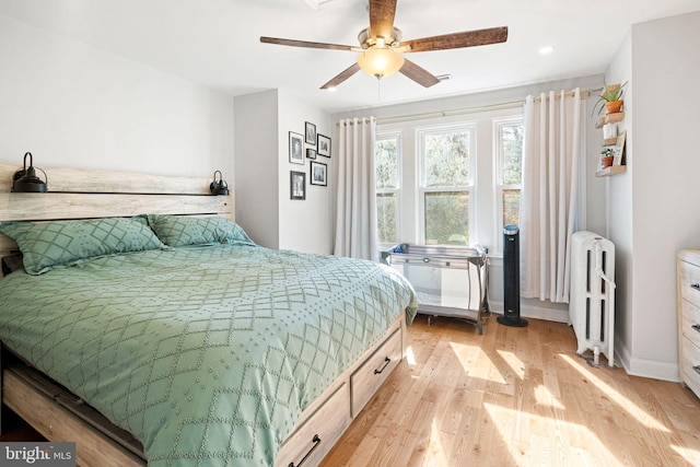 bedroom featuring light hardwood / wood-style floors, ceiling fan, and radiator