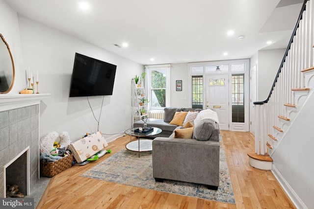 living room with wood-type flooring and a tile fireplace