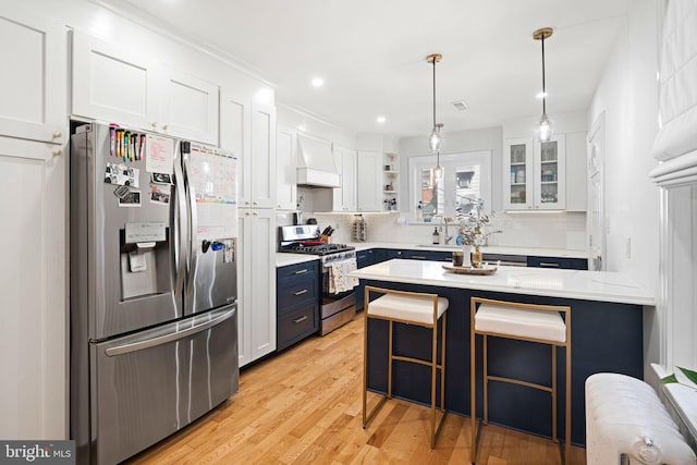 kitchen featuring white cabinets, a kitchen bar, appliances with stainless steel finishes, and light wood-type flooring