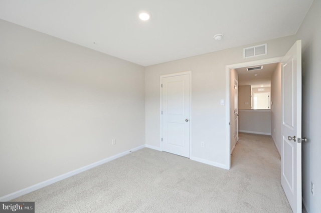 unfurnished bedroom with light colored carpet and a closet