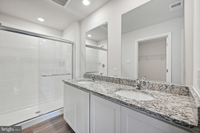 bathroom with hardwood / wood-style floors, vanity, and a shower with door