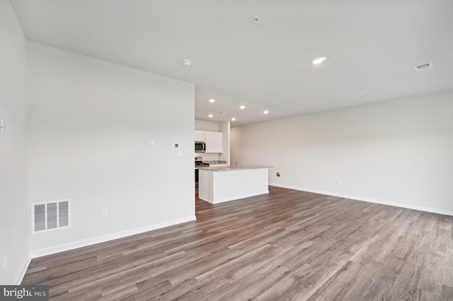 unfurnished living room with sink and light hardwood / wood-style flooring