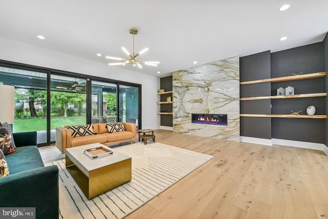 living room featuring a chandelier, a fireplace, and light hardwood / wood-style floors