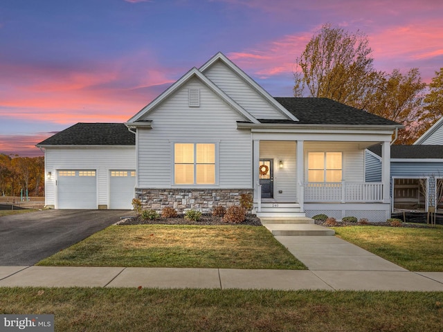 view of front of property with covered porch, a garage, and a lawn