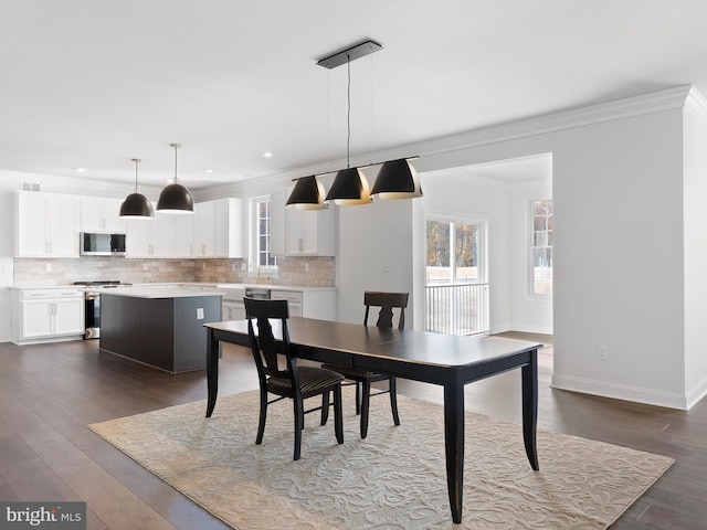 dining space featuring dark wood-type flooring and crown molding