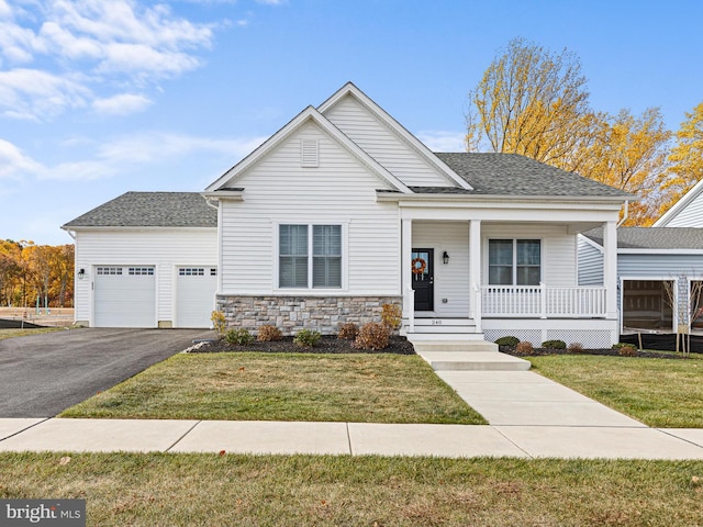 view of front of house featuring a front yard, covered porch, and a garage