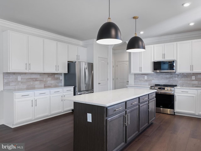 kitchen featuring stainless steel appliances, hanging light fixtures, a kitchen island, white cabinets, and dark wood-type flooring