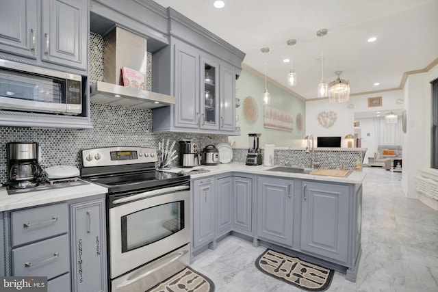 kitchen featuring gray cabinetry, stainless steel appliances, wall chimney range hood, pendant lighting, and kitchen peninsula