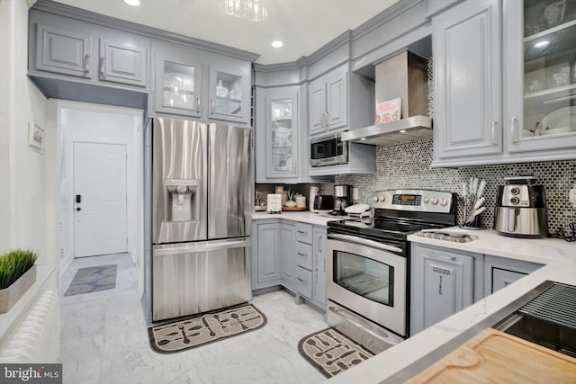 kitchen with appliances with stainless steel finishes, wall chimney range hood, and gray cabinetry