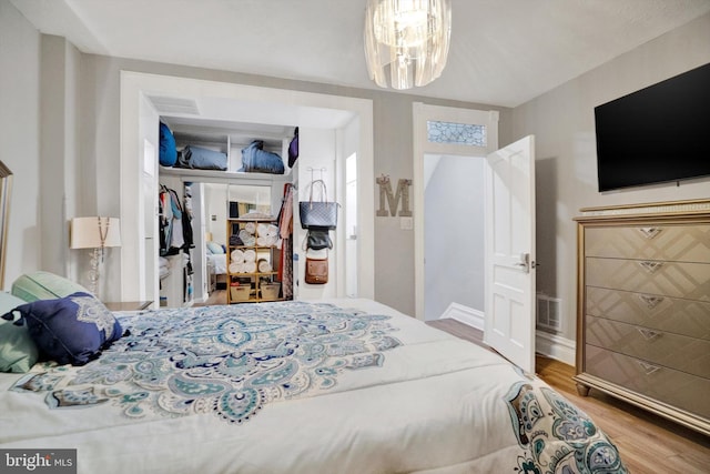 bedroom with hardwood / wood-style flooring and a notable chandelier