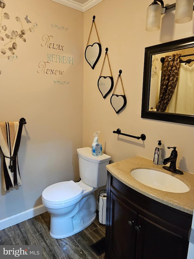 bathroom featuring toilet, wood-type flooring, crown molding, and vanity