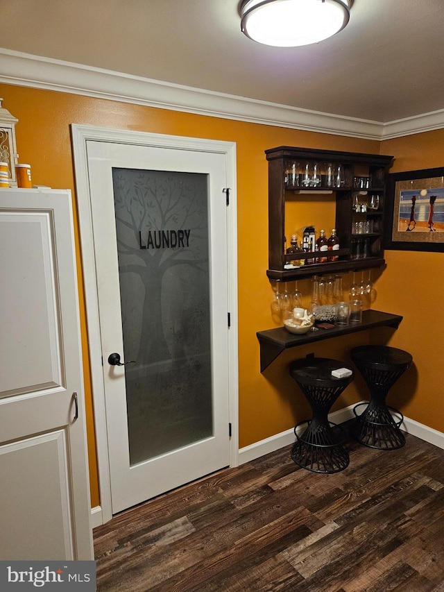 bar with dark hardwood / wood-style flooring, dark brown cabinets, and crown molding