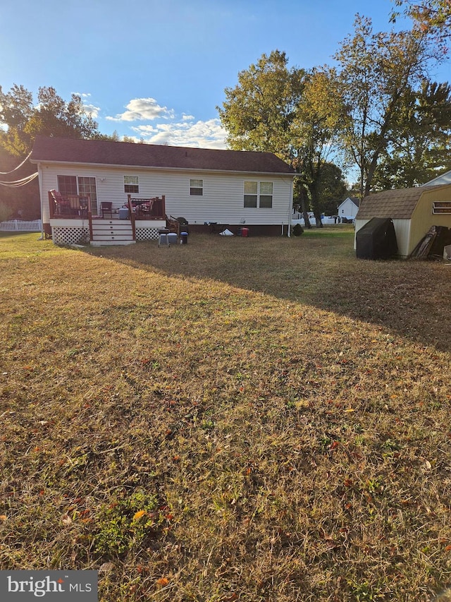 back of property with a wooden deck and a yard