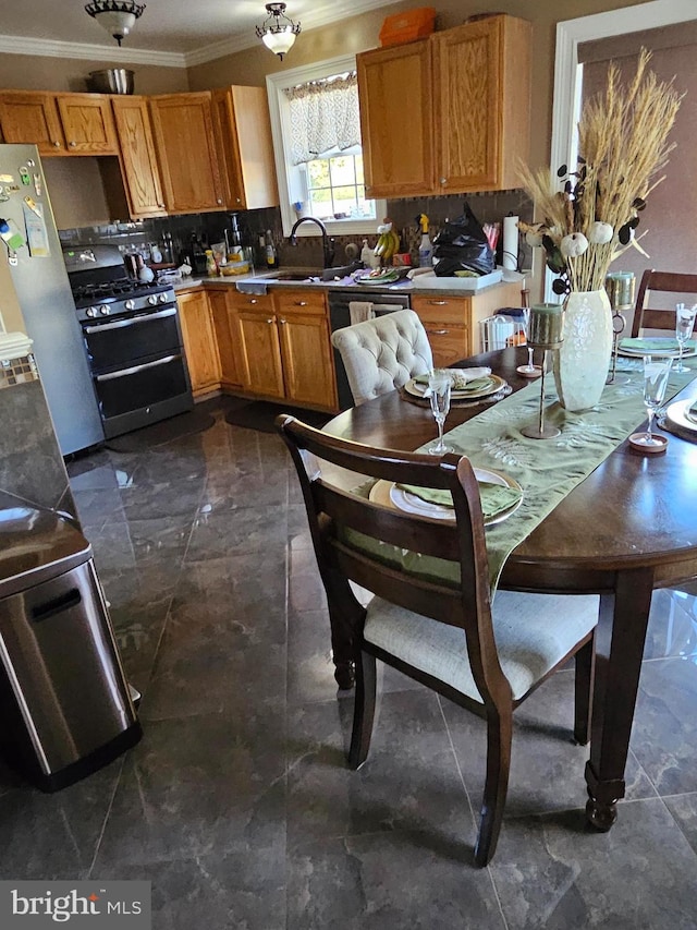 kitchen featuring stainless steel gas range oven, sink, crown molding, and tasteful backsplash