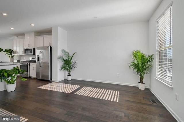 interior space featuring appliances with stainless steel finishes, dark hardwood / wood-style flooring, white cabinetry, and a healthy amount of sunlight