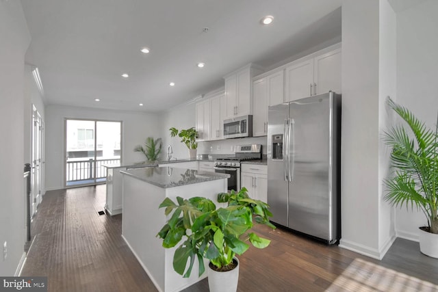 kitchen with kitchen peninsula, white cabinetry, stainless steel appliances, and dark hardwood / wood-style floors