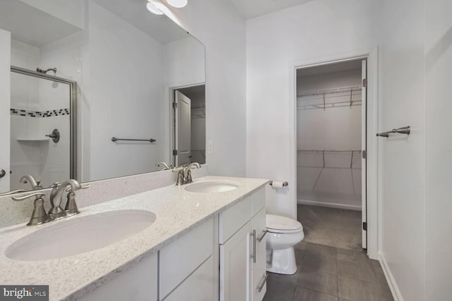 bathroom with tile patterned flooring, vanity, toilet, and walk in shower