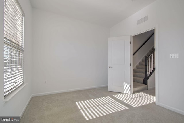 spare room with light carpet and vaulted ceiling