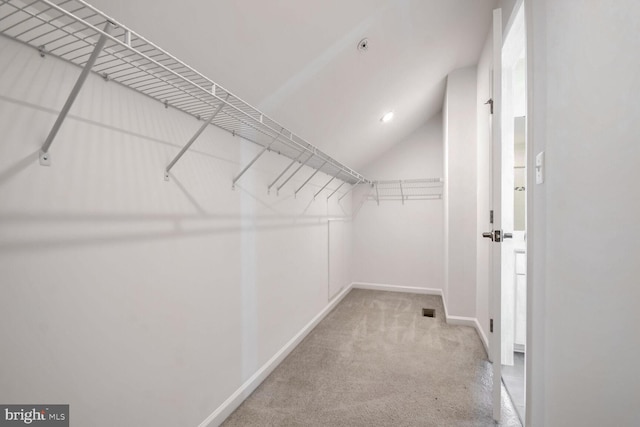 walk in closet with light carpet and lofted ceiling