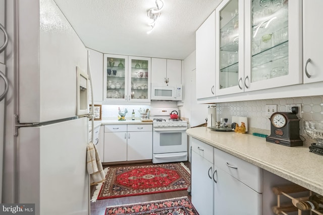 kitchen featuring white cabinets, white appliances, a textured ceiling, and decorative backsplash