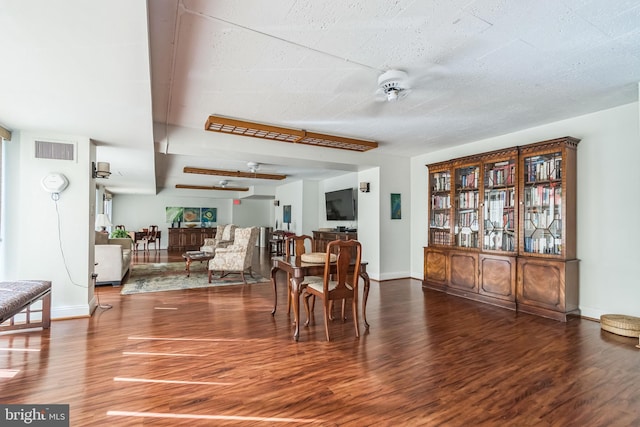 dining room featuring dark wood-type flooring, ceiling fan, and a textured ceiling