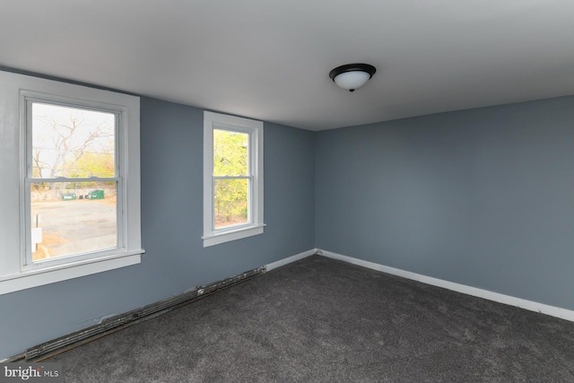 spare room featuring dark carpet