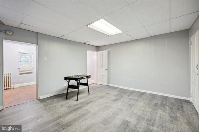 interior space featuring radiator, wood-type flooring, and a drop ceiling