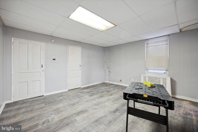 basement featuring a drop ceiling and wood-type flooring