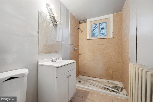 bathroom with tile patterned flooring, radiator, a tile shower, vanity, and toilet