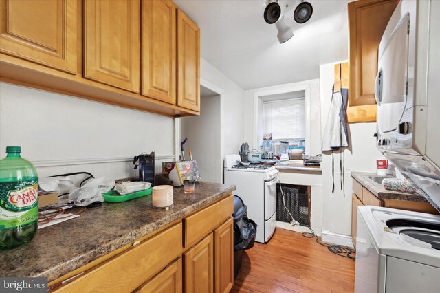 kitchen featuring white range with gas stovetop, light hardwood / wood-style floors, and washer / dryer