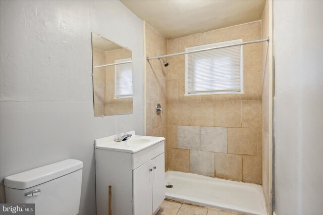 bathroom with toilet, vanity, tile patterned floors, and tiled shower